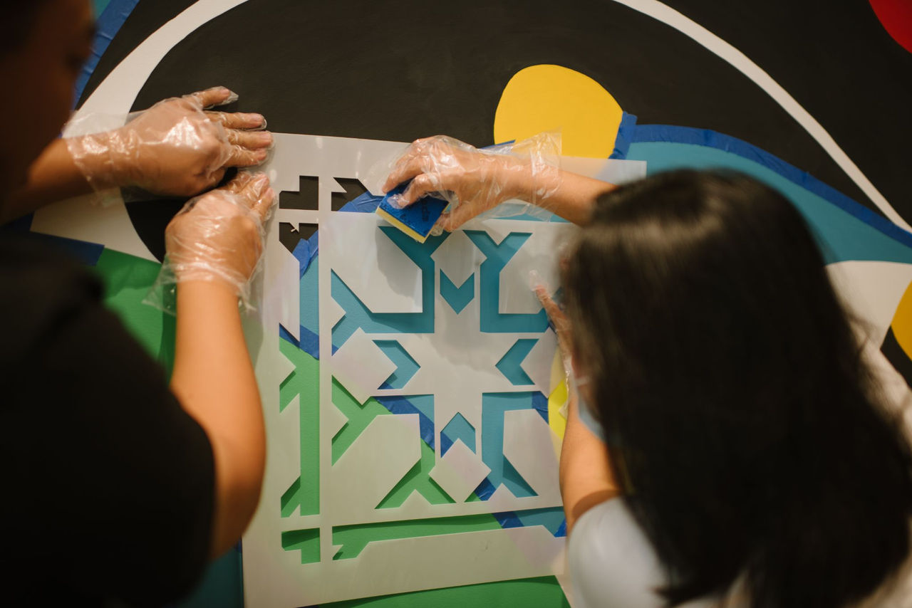 Two associates painting a mural on an office wall