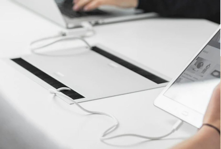 Closed desk outlet panel, with a tablet plugged into it