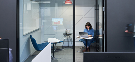 Glass-walled phone room or small meeting space with two chairs
