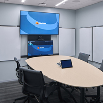 Collaboration space with an oval table, chairs, and a large monitor