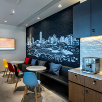 Office kitchenette featuring dark cabinetry and a distinctive city skyline backsplash