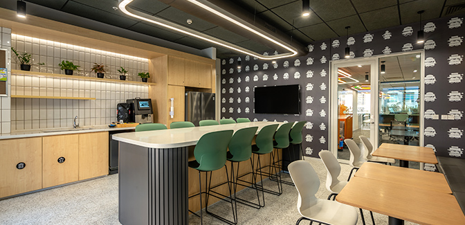 Modern office kitchen and dining area with bar seating and stylish decor