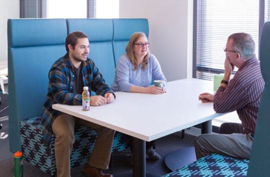 A group of people sit in a booth with various drink containers