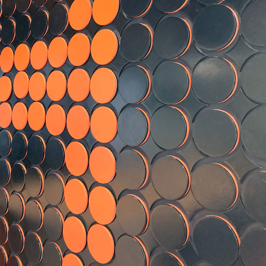 decorative wall art comprised of orange and black circles in a grid