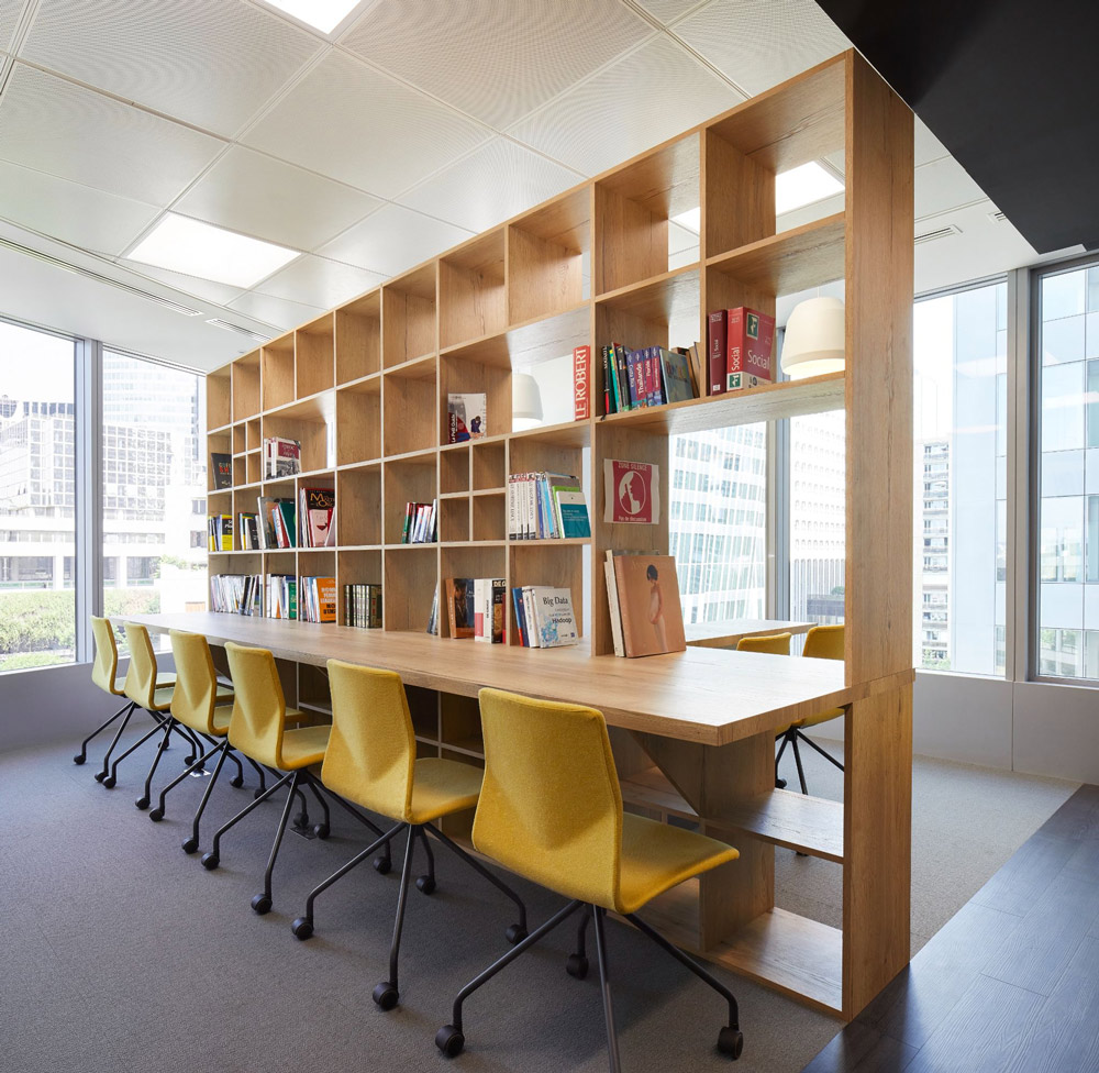 a floor to ceiling book shelf divided into squares with a desktop running its length