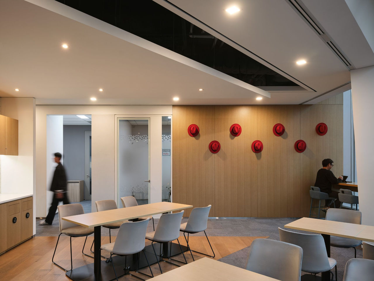 an office space featuring a wooden wall adorned with Red Hat fedoras