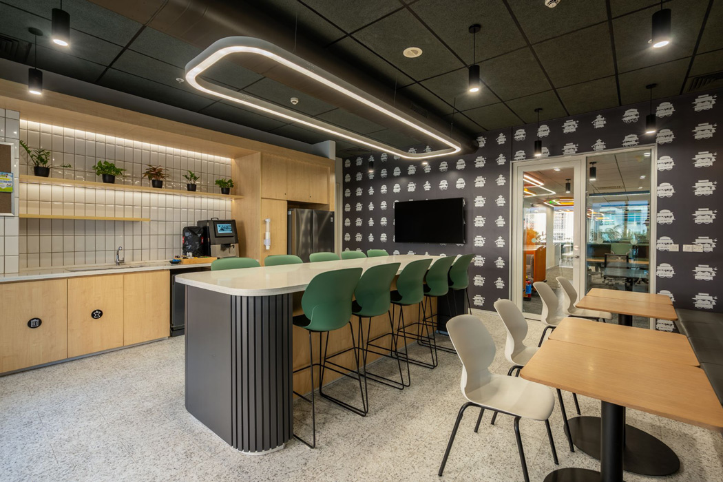 a break area with wood paneled cabinets and a center counter height bar table with green stools