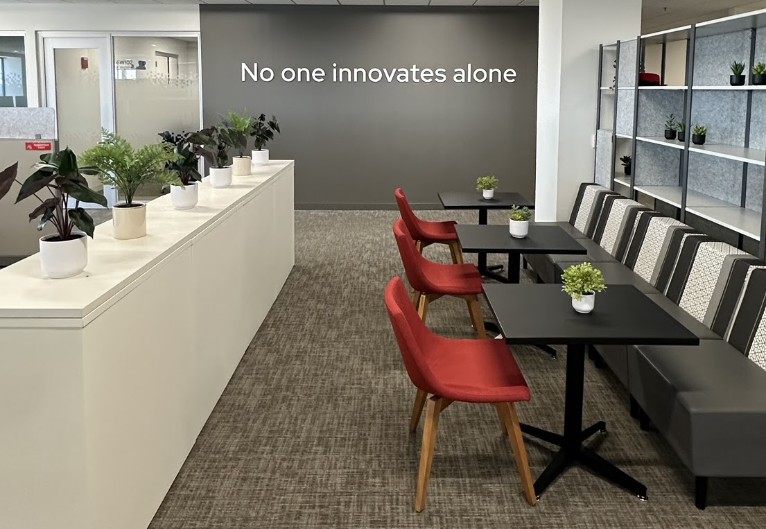 an open common area with white wall lined with plants