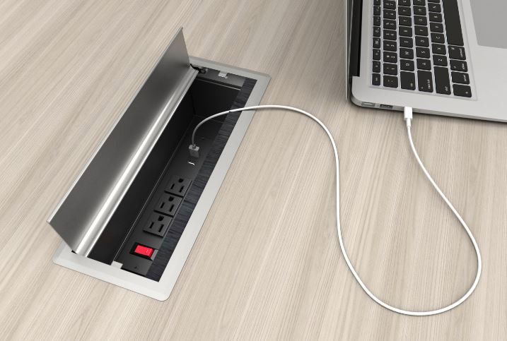 Open desk outlet panel, with a laptop plugged into it