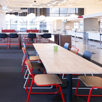 Spacious cafeteria with long wooden tables.