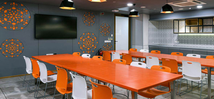 Cafeteria with orange tables and chairs.