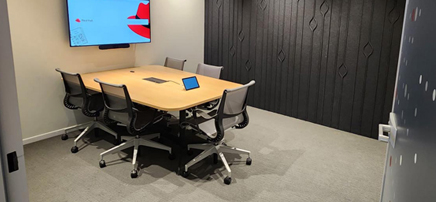 Small meeting room with wooden table and screen.
