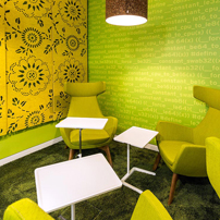 Vibrant lounge with lime green wall and yellow chairs.