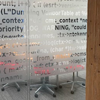 View through a glass wall with frosted text into a conference room with a long table and chairs
