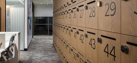 Close-up detail of light wood lockers featuring black circular number labels and keyholes