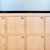 Bank of light wood lockers with silver handles and numbers, below a frosted glass panel