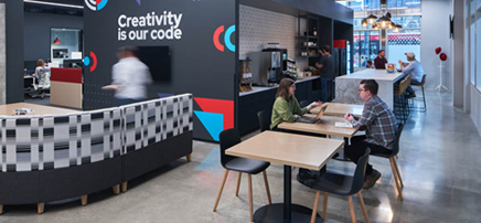 Spacious cafe-style office pantry with varied seating options, patterned tile backsplash, and industrial-style ceiling