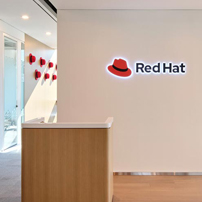Simple reception desk with a 'Red Hat' logo on the white wall above