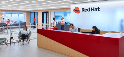 Modern red and white reception desk with a large 'Red Hat' logo