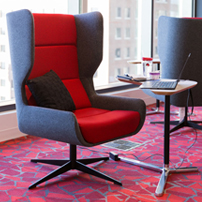 Modern red and grey high-back swivel chair with a small side table on a patterned red carpet