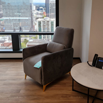 Quiet office corner with armchair, city view, and a phone on a round table.