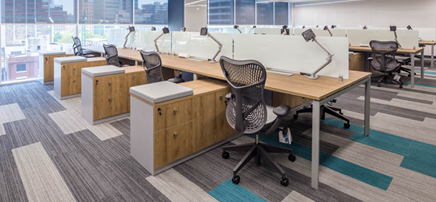 Modern office with angled desks, geometric lighting, and patterned carpet